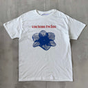 White t-shirt with blue flower graphic and 'cocteau twins' text on a gray surface